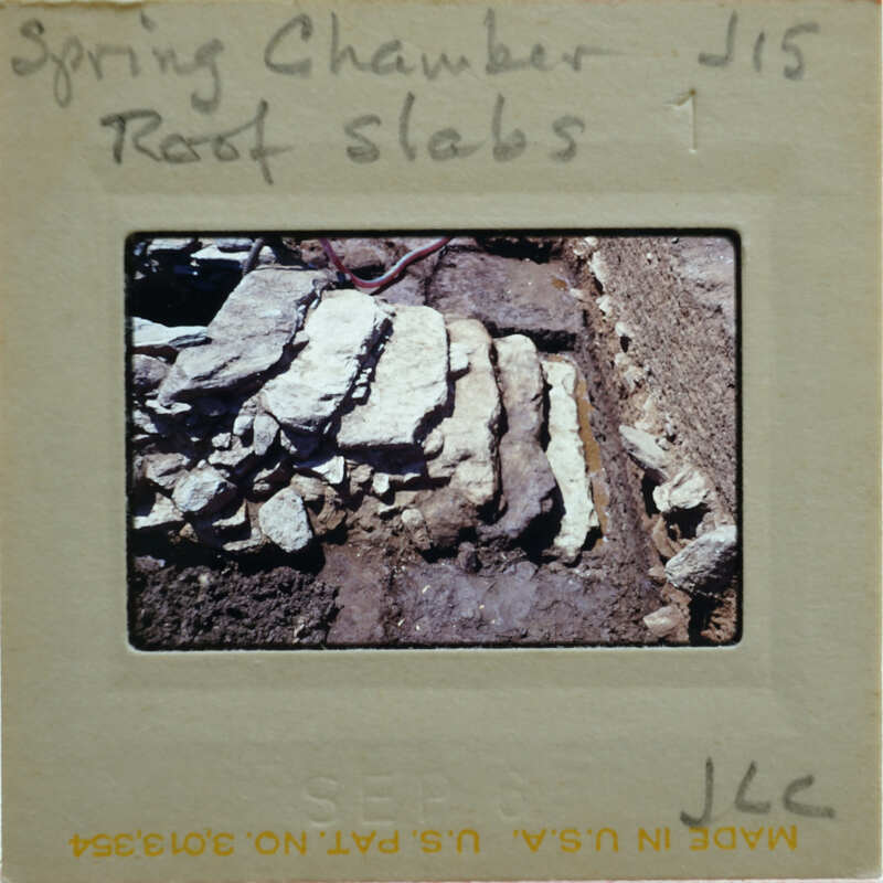A photograph of a broken stone slab with a handwritten description and number on the back.