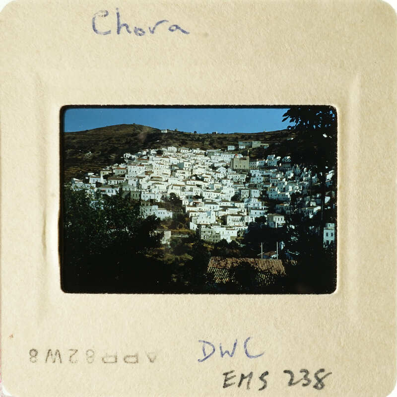 A photograph of a mountainous village with houses and trees, taken during daylight hours.