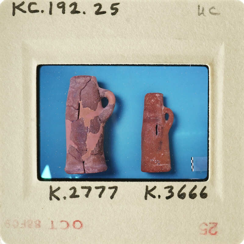 Two ancient clay artifacts, possibly pottery handles, displayed on a blue surface with a white border and label containing numbers.