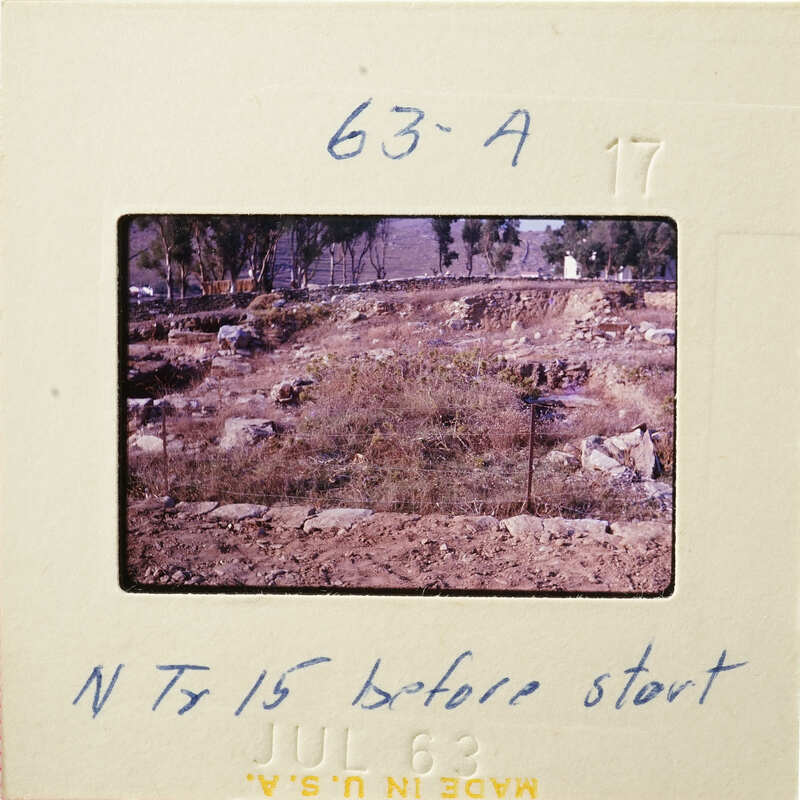 This is an old photograph showing a dirt area with trees and shrubs, possibly taken before construction started.