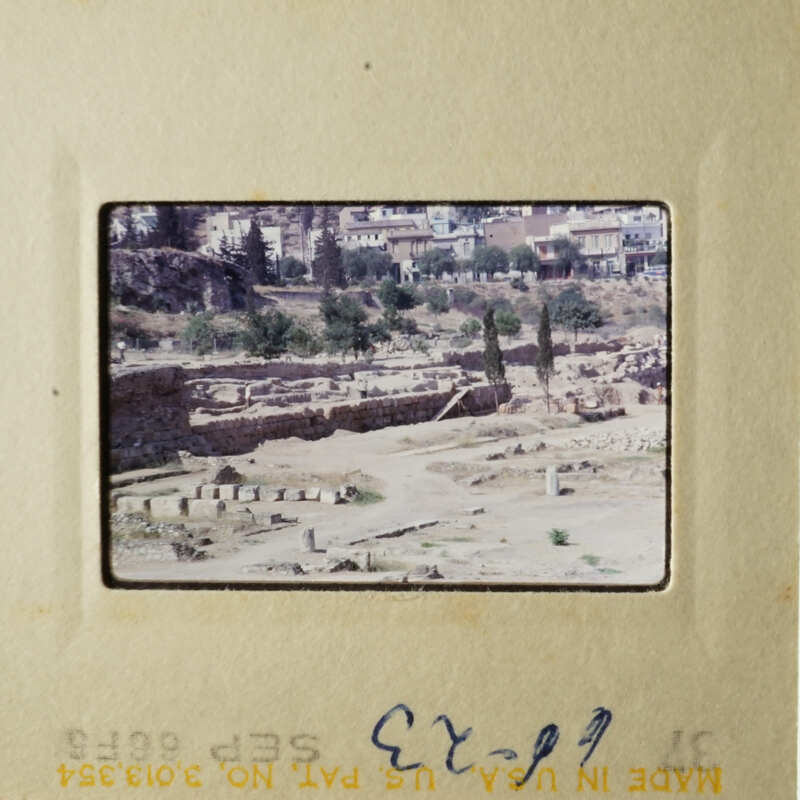 This is an image of a photo album page with a photograph of an ancient city, possibly in Greece, featuring ruins and a modern town in the background.