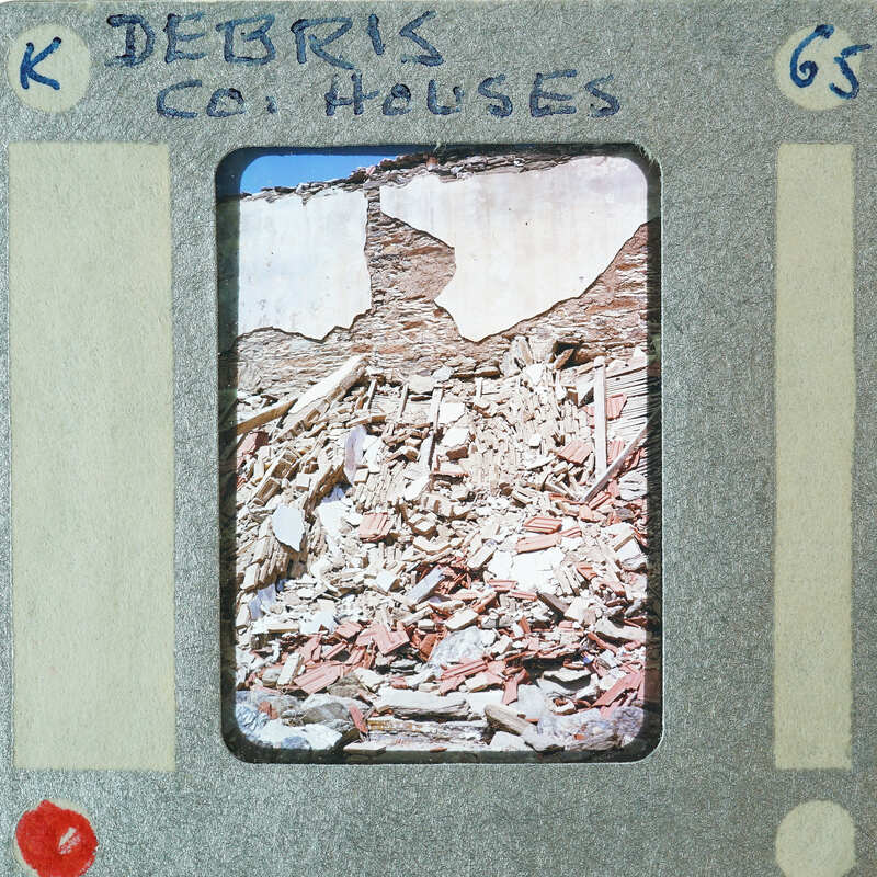 Picture of a destroyed building with debris on the ground, framed by film strip borders.