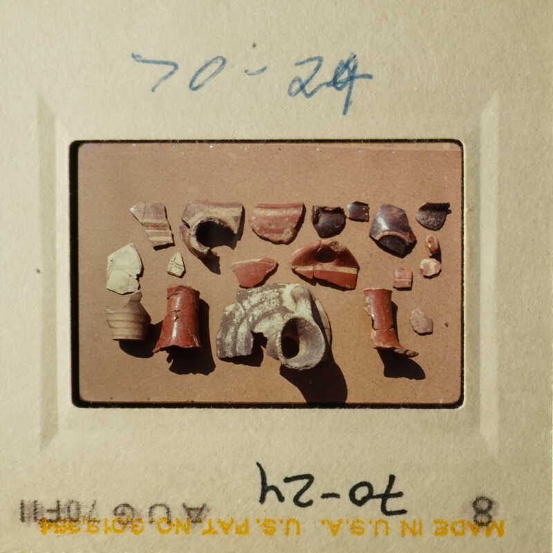 The photo shows an array of broken pottery pieces on a table, including shards and fragments.