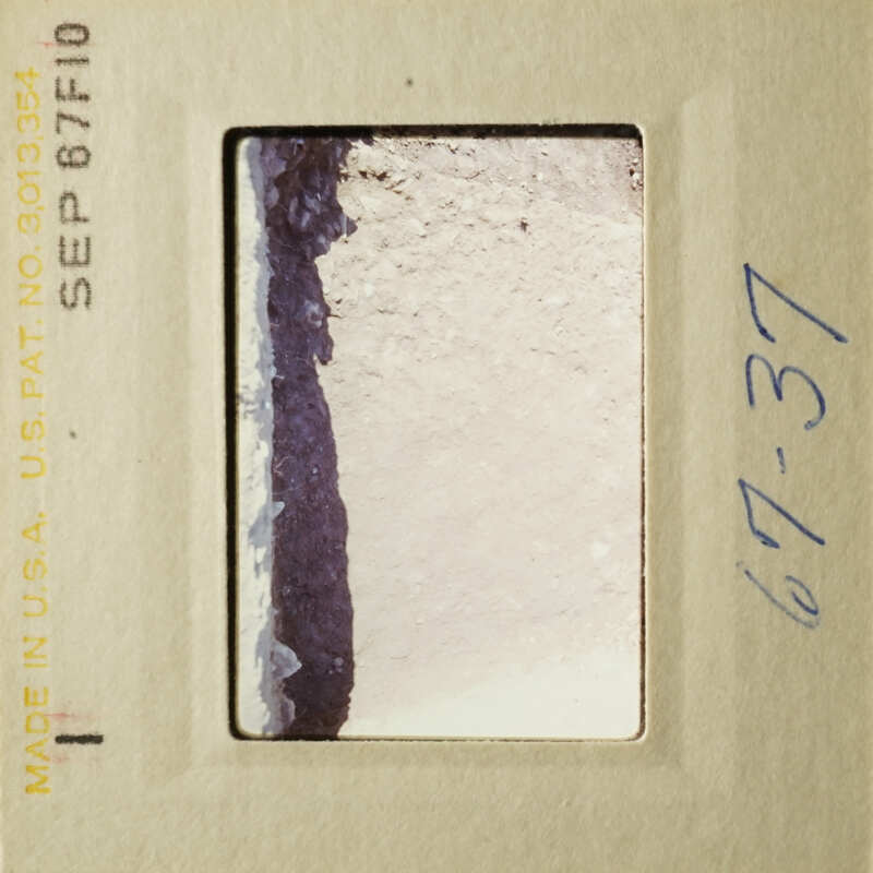 "A vintage photo in a frame, showing a close-up of a surface with dirt and debris."