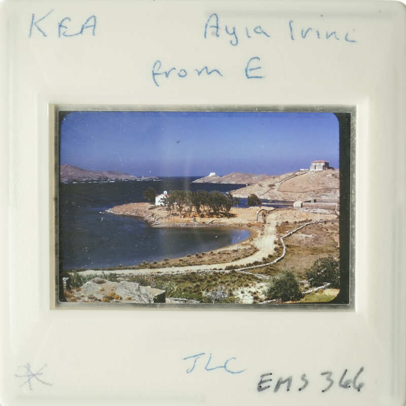 A photograph of an island with buildings and a body of water, framed by white borders.