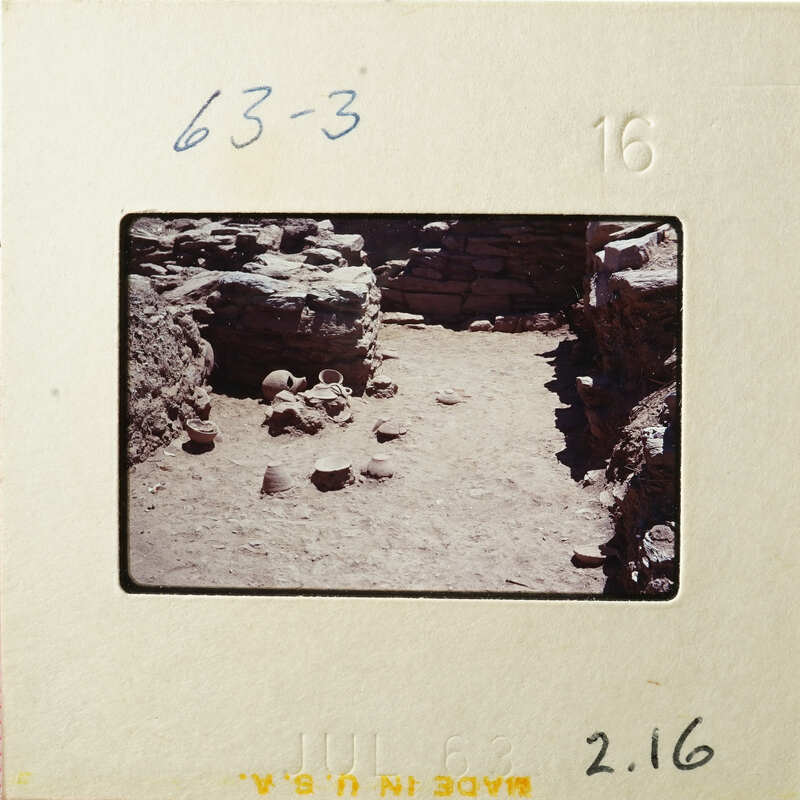 A photograph showing an archaeological site with ruins and scattered stones.