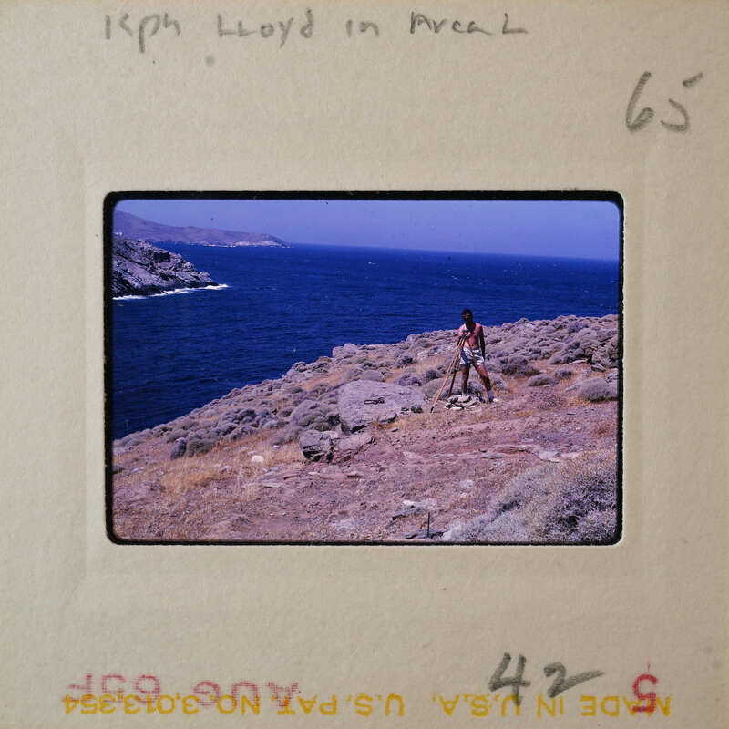 A photo of a person standing on a cliff overlooking the ocean with a vintage look.