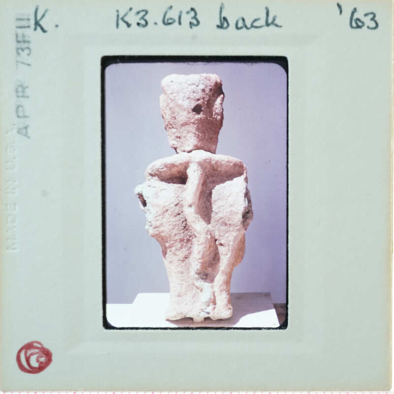 Ancient clay figurine on display with a label and date stamp.