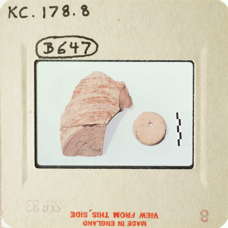 Ancient artifact on a white surface, with a smaller object beside it.