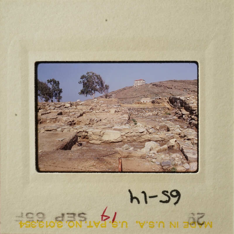 This is an old photograph showing ruins on a hillside with trees and clear sky.