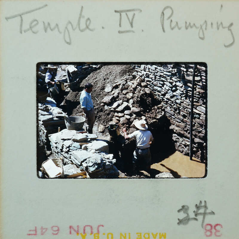 Three workers working on stone walls, partially under muddy water.