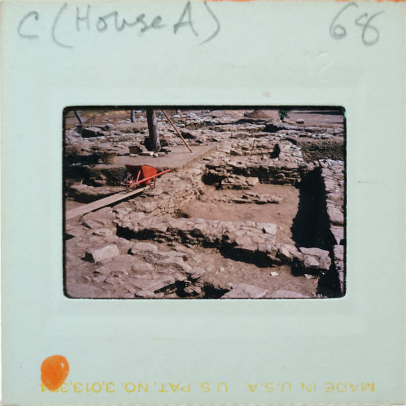 A photograph of an archaeological site with exposed ruins and stone foundations.