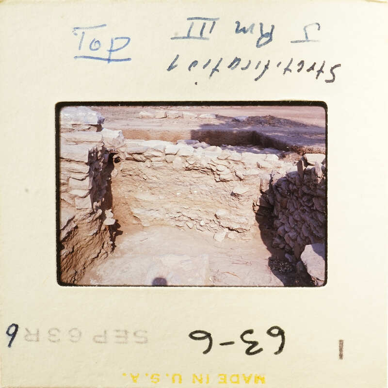 This is an image of an ancient archaeological site with stone ruins and a dirt floor.