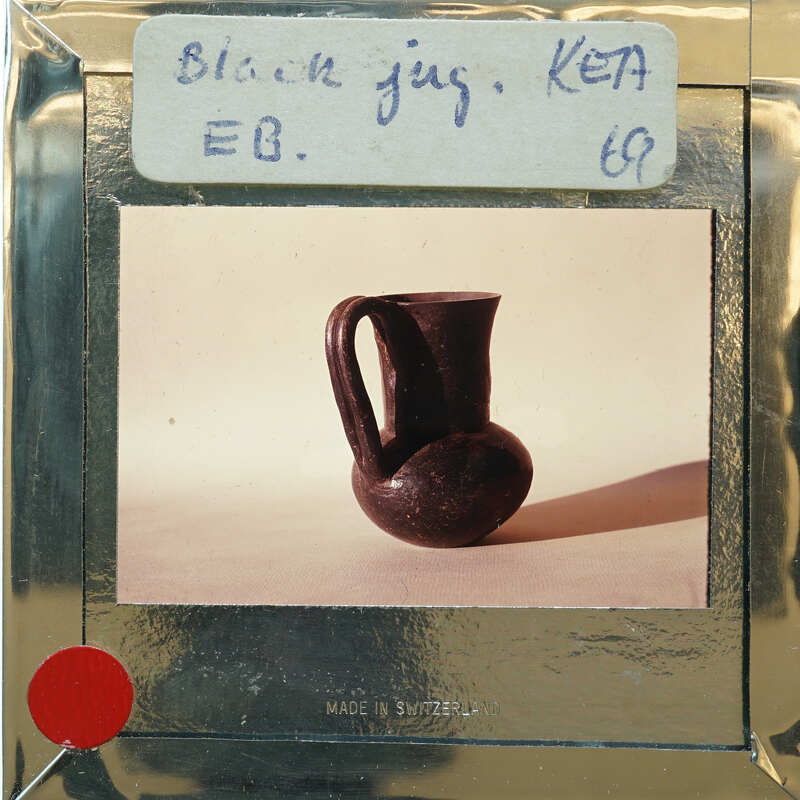 Photo of a black clay vase with handwritten label on a card.