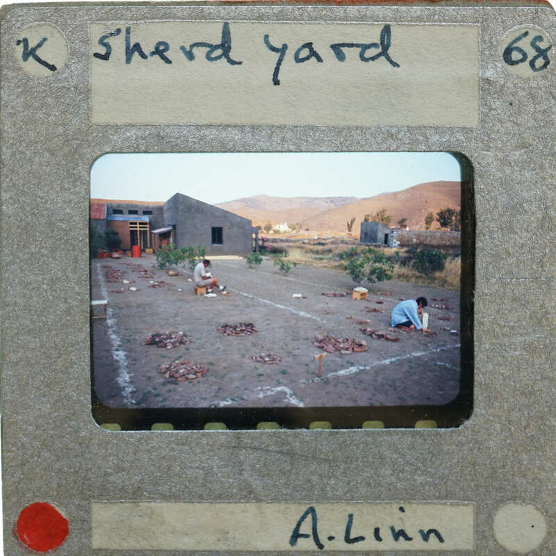 A vslide of people working on a field drying sherds.