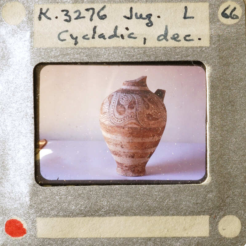 A small, intricately decorated vase with a handle on display.