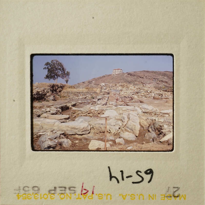 Ruins on hillside with vegetation and sky.