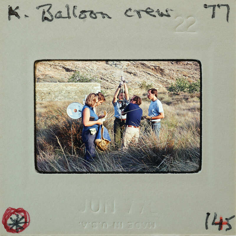 A group of people standing outdoors, possibly a balloon crew preparing equipment.