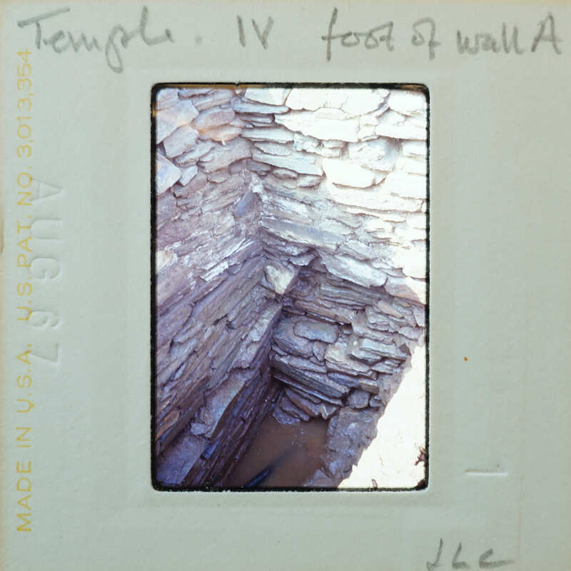 Interior corner of stone wall with water collecting on floor.