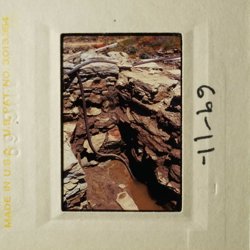 This is an image of a rocky, excavated area with exposed layers and piping, possibly a construction site or geological feature.