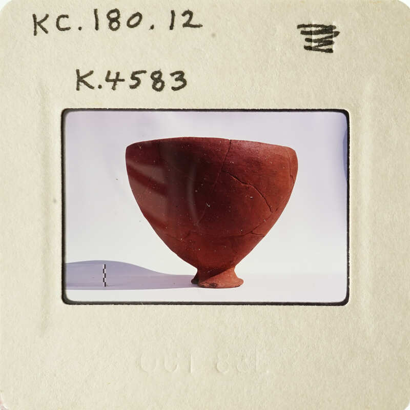 Ancient clay pot with visible cracks and imperfections, photographed against a white background.