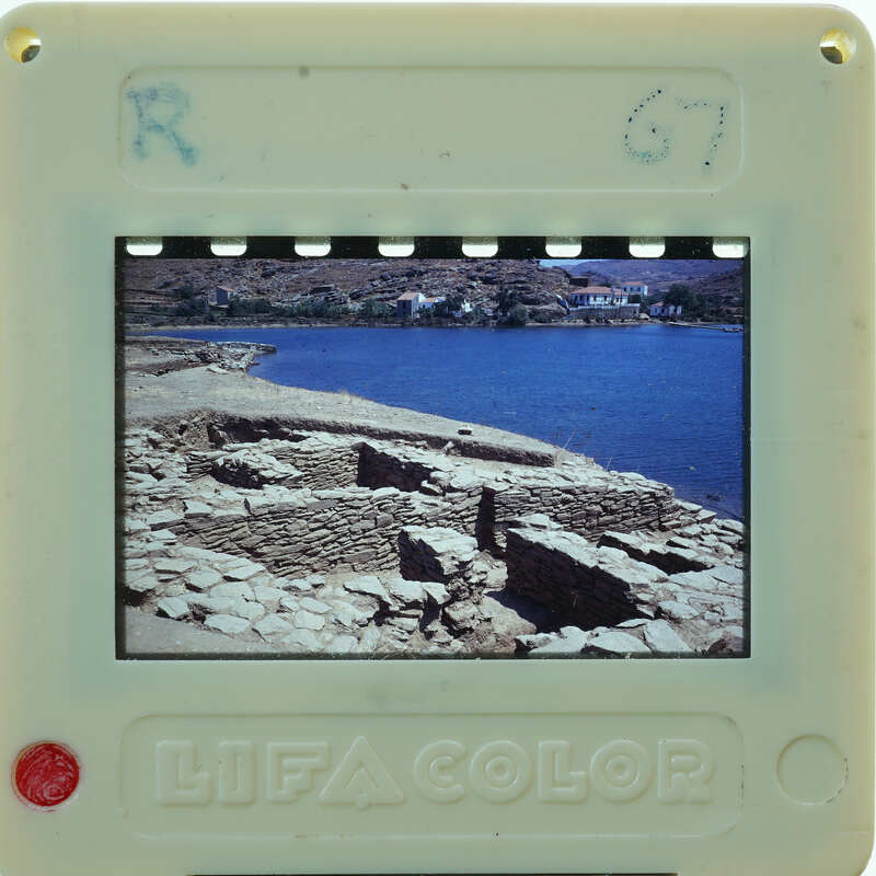 A plastic film strip viewer displaying a photograph of ancient ruins by the water.