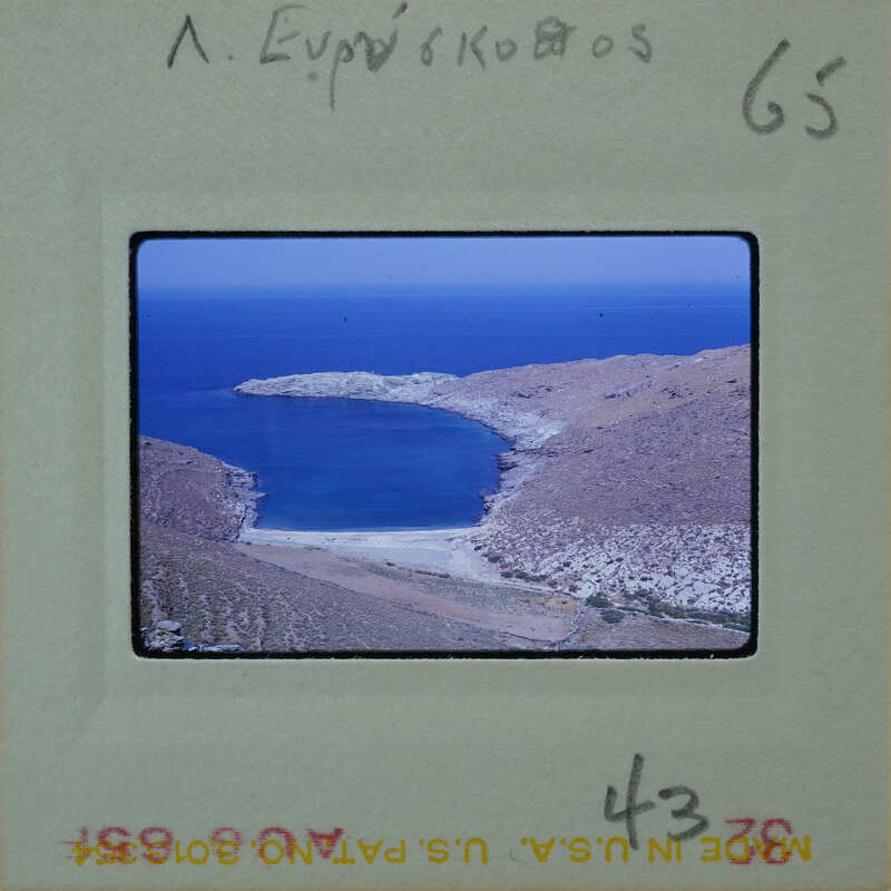 A photograph of a serene coastal landscape with clear blue water and rocky hillsides.