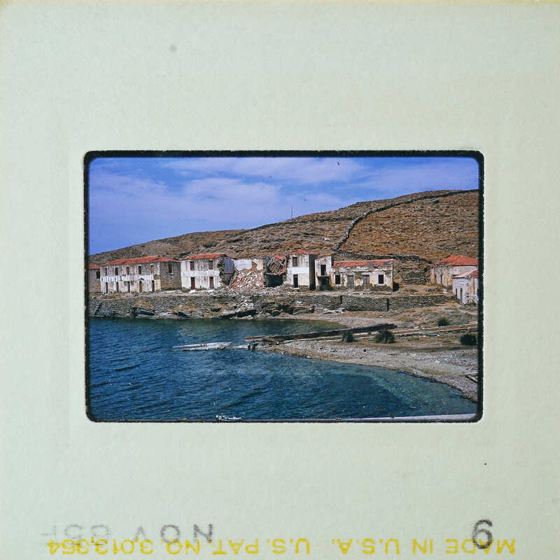 A photograph of a seaside village with abandoned houses and boats on the shore.