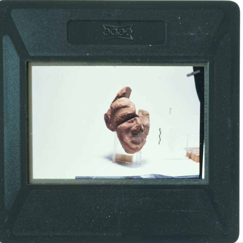 A small, dark brown sculpture of a human head on display.