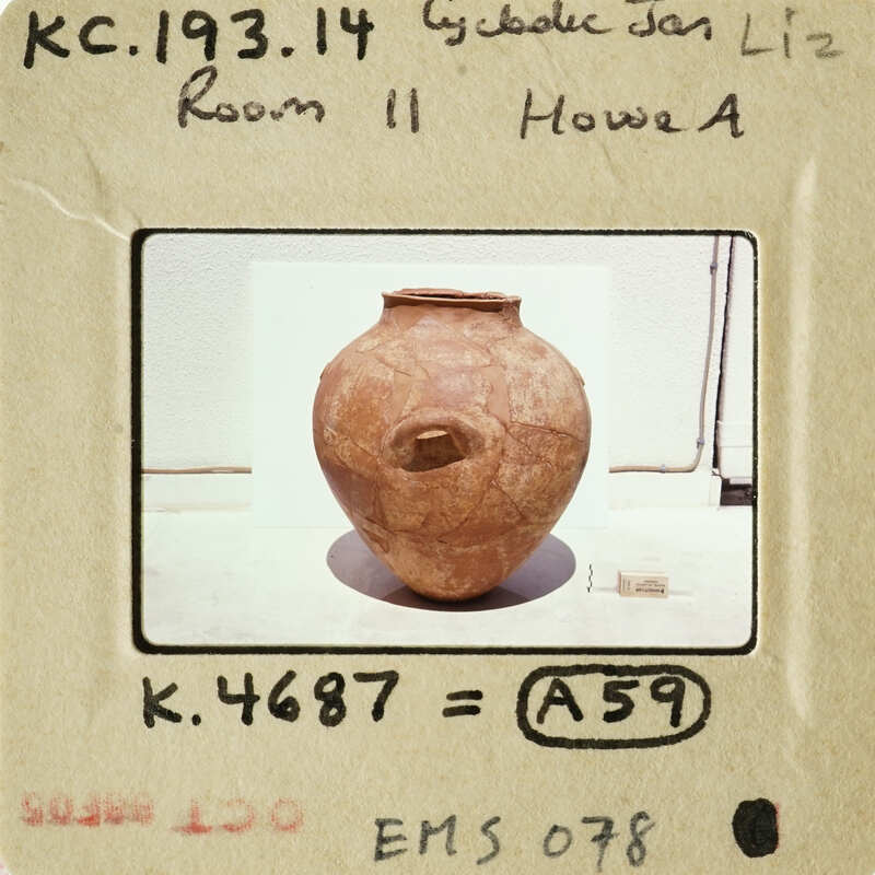 This is an image of a clay pot with a handle, placed on a surface.