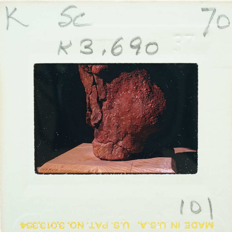 A photograph of a red, jagged rock on display with an information card.