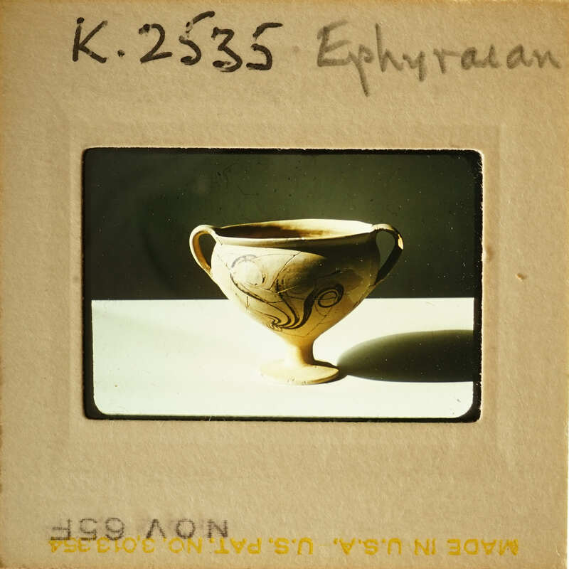 Ancient Greek amphora with intricate designs, photographed on a white surface.