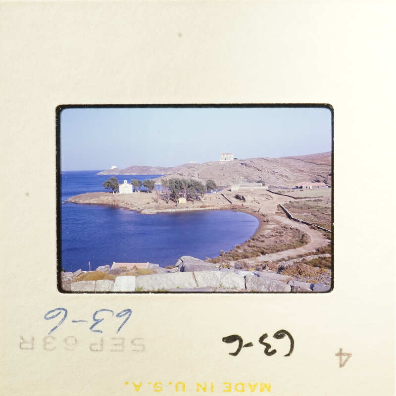 A photograph of an island with houses and vegetation, surrounded by water under a clear sky.