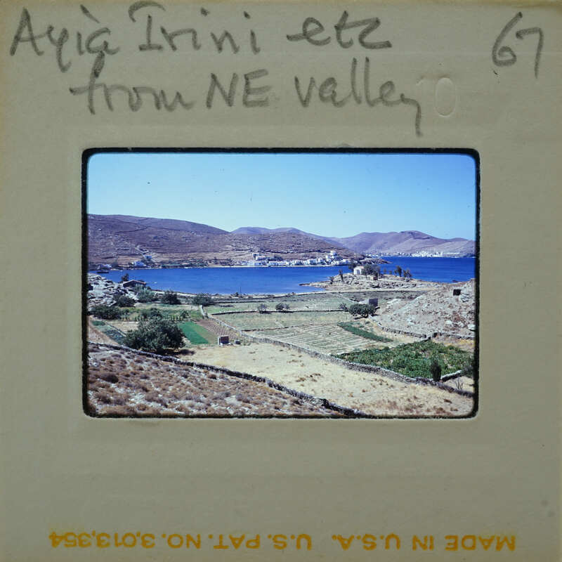 A vintage photo of a scenic landscape with blue water, mountains, and fields.