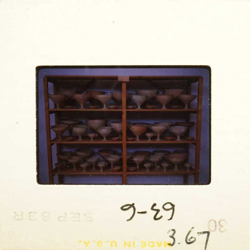 Row of dark brown vases on shelves.