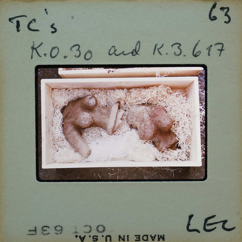 Small clay figurines inside a box with straw lining.