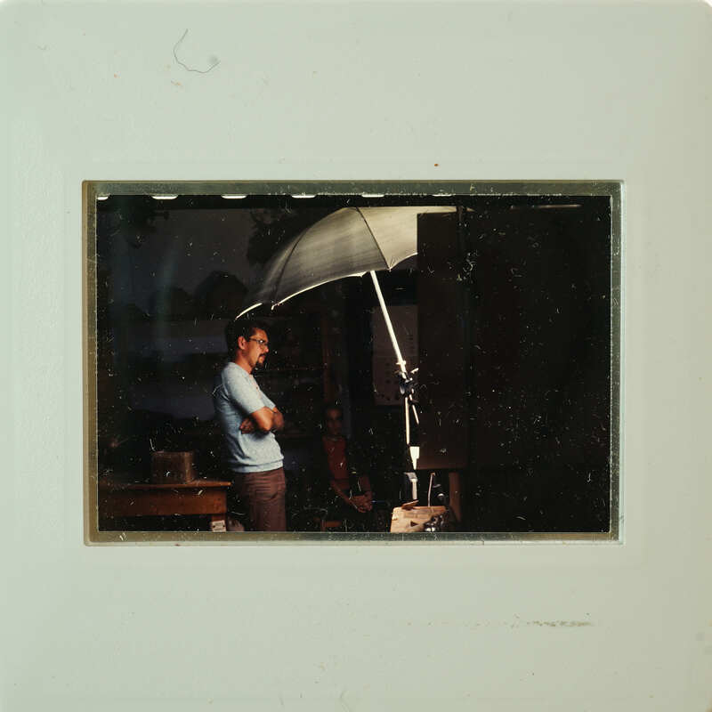 Man standing under an umbrella with his arms crossed.