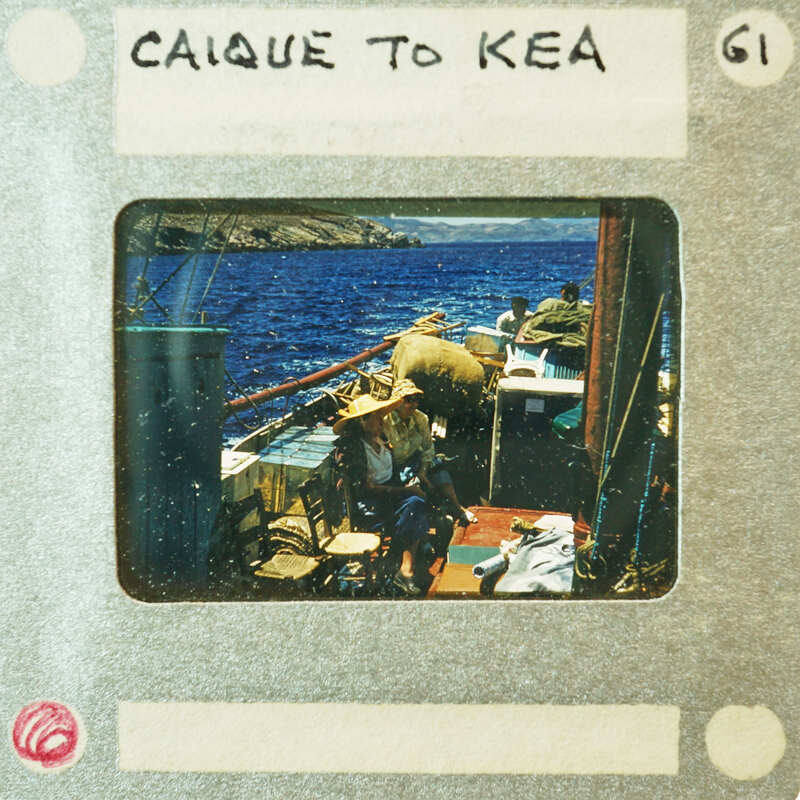 A vintage photo of a man and woman sitting on the deck of a boat with water in the background.