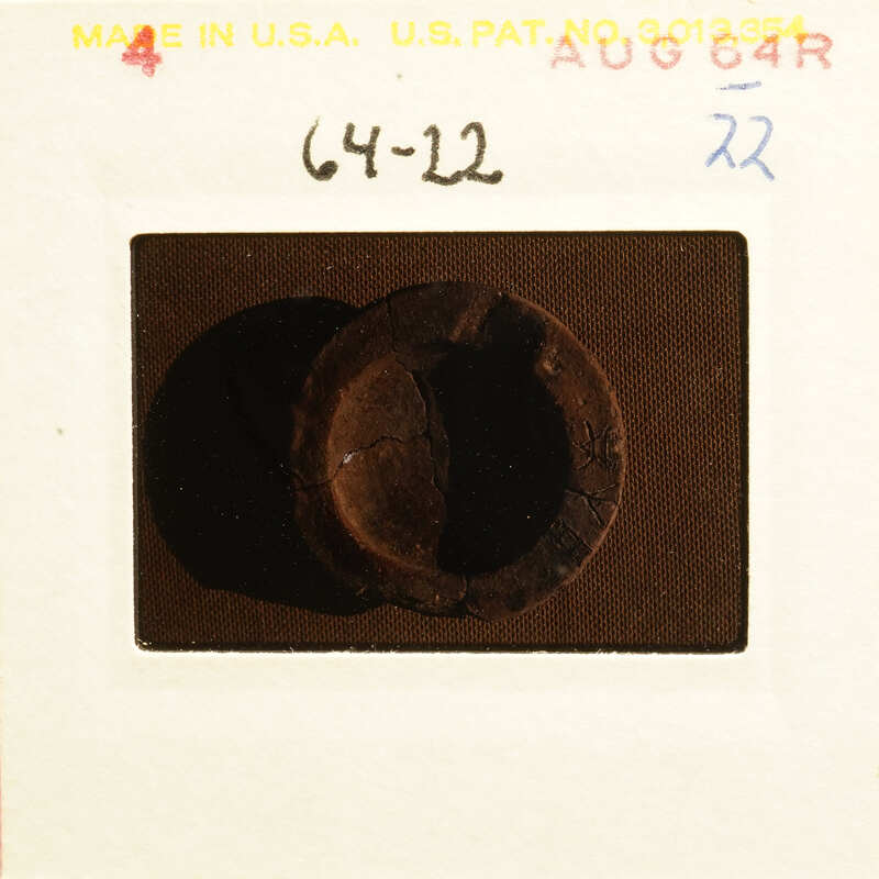 A close-up photograph of an object with a worn surface, possibly metal, on a dark background.