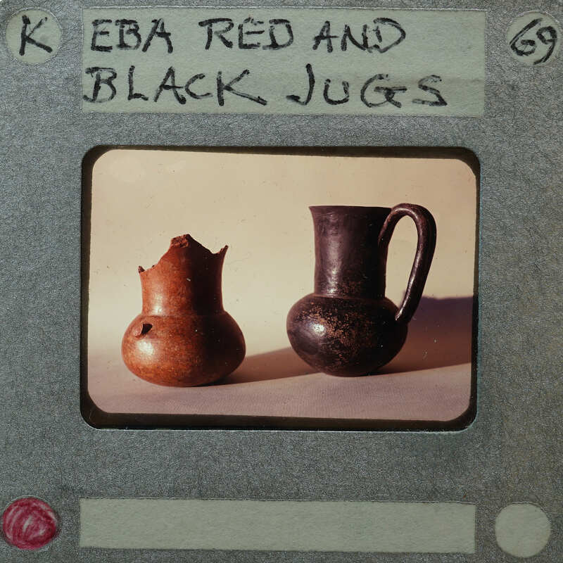 Two clay pots, one black and one red, displayed on a table with a label that reads "EBA Red and Black Jugs".