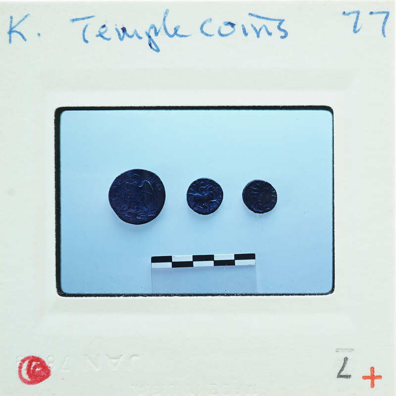 Three coins with a face-like arrangement on a white surface.