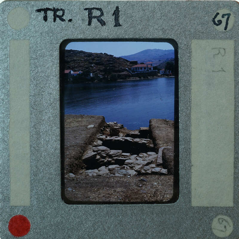 A vintage film strip with a photograph of a rural landscape featuring water and mountains.