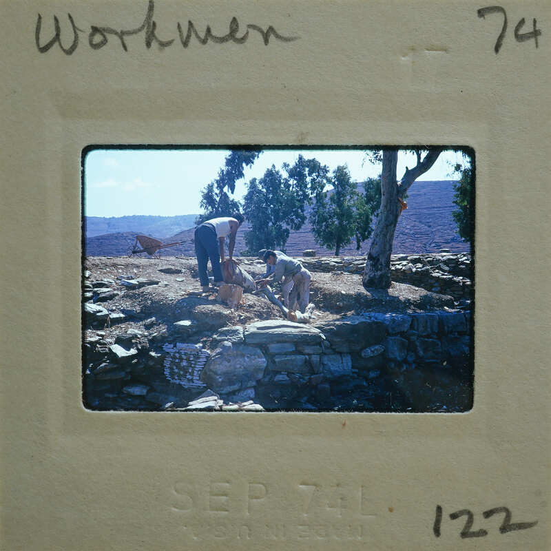 Two men working on a stone structure, possibly archaeological excavation.