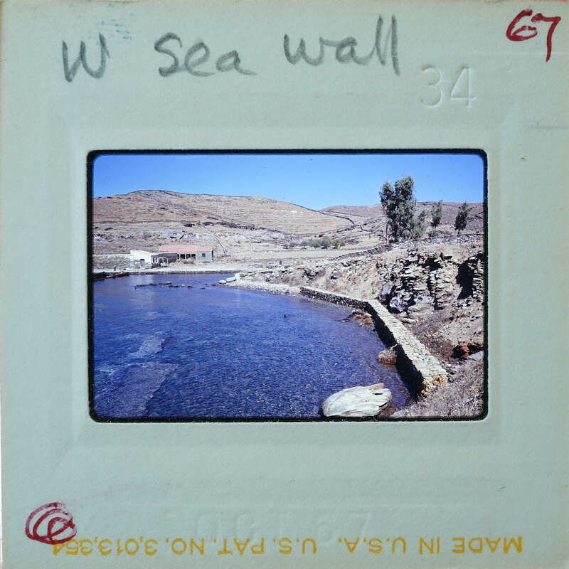 A coastal landscape featuring water, rocks, and buildings.