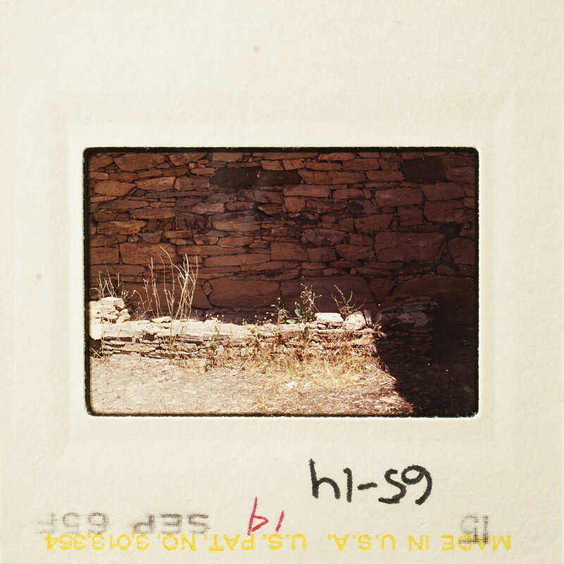 Old stone wall with vegetation and shadow.