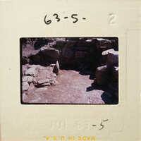 Ancient ruins with stone structures and dirt ground, photographed on film.