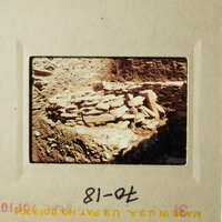 This is an old photograph depicting a rock wall and stone ruins, likely taken from a distance.