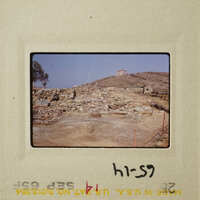 The photograph shows an ancient archaeological site with ruins and a hilltop view.