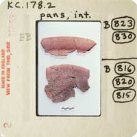 Photograph of two broken red ceramic pieces with visible cracks and missing parts, displayed on a white surface.