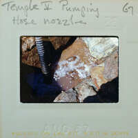 Hose for pumping water in a flooded floor surface, surrounded by stones.